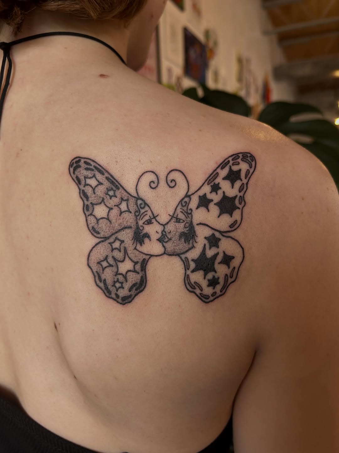 A butterfly with star-filled wings tattooed on a shoulder blade